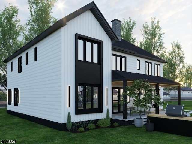 back of property with board and batten siding, a yard, and a chimney