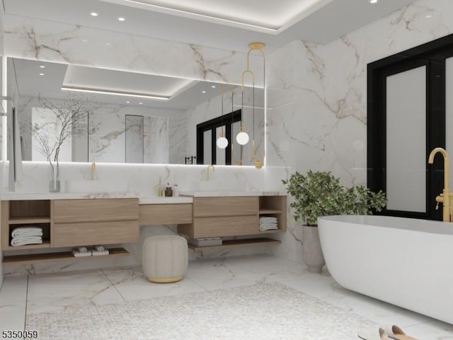 full bath with vanity, recessed lighting, stone wall, a freestanding bath, and marble finish floor