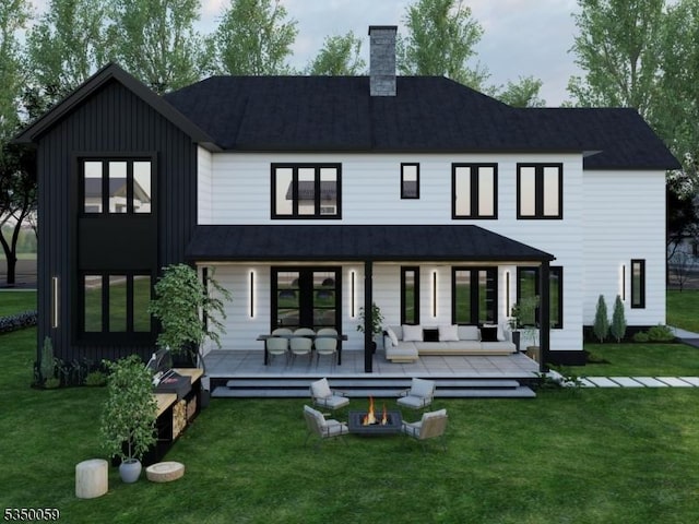 back of house featuring roof with shingles, board and batten siding, a chimney, and a lawn