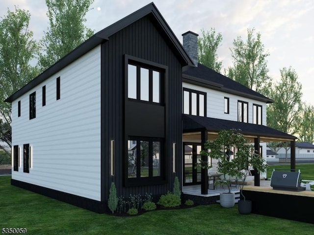rear view of house with board and batten siding, a chimney, and a lawn