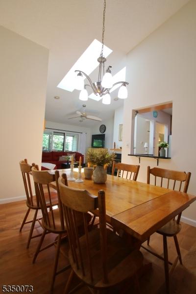 21 Crabapple Ln, Franklin Twp, NJ 08823 - dining area featuring baseboards, a chandelier, a ceiling fan, a towering ceiling, and wood finished floors