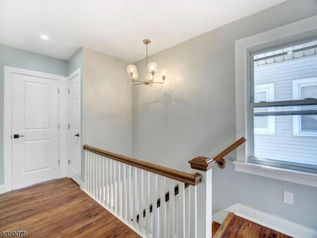 stairs with wood finished floors, a notable chandelier, and baseboards