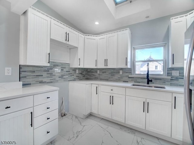 kitchen with tasteful backsplash, white cabinetry, recessed lighting, marble finish floor, and a sink