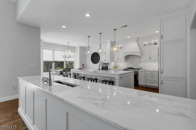 kitchen with a sink, white cabinetry, appliances with stainless steel finishes, and custom exhaust hood