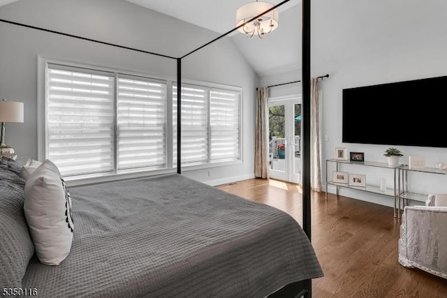 bedroom featuring access to outside, lofted ceiling, and wood finished floors