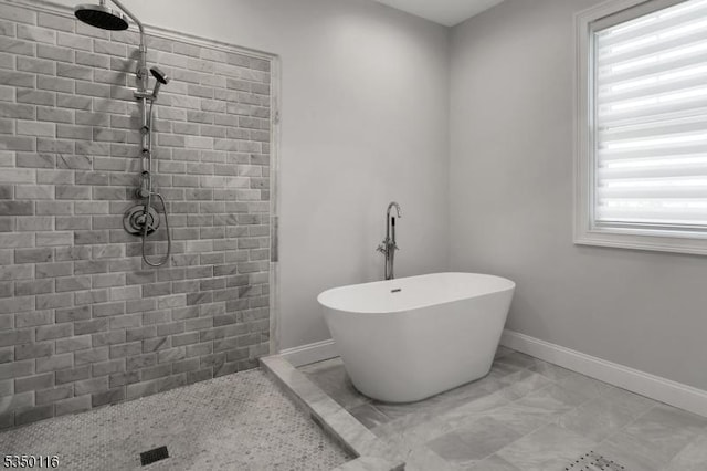 bathroom featuring baseboards, tiled shower, and a soaking tub