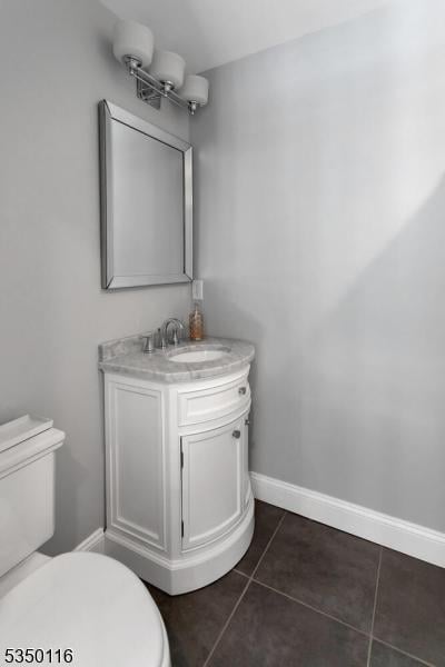 bathroom with toilet, baseboards, tile patterned flooring, and vanity