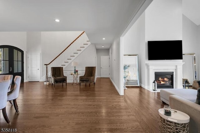interior space with stairs, a glass covered fireplace, wood finished floors, recessed lighting, and arched walkways