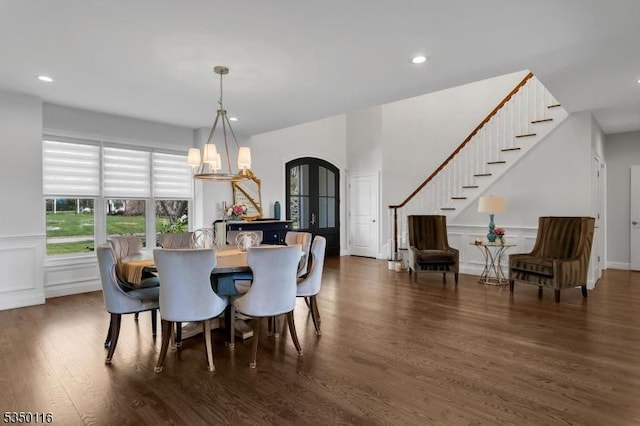 dining area featuring an inviting chandelier, arched walkways, recessed lighting, wood finished floors, and stairway
