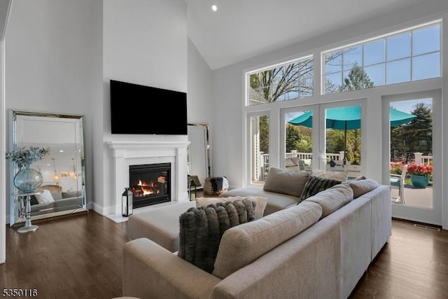 living area with a fireplace with flush hearth, high vaulted ceiling, french doors, and dark wood finished floors