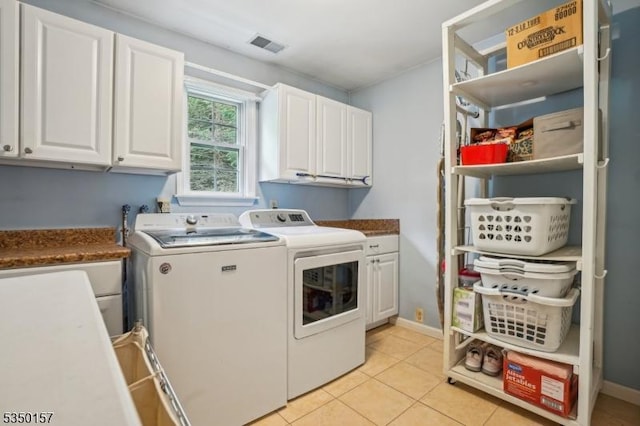 laundry area featuring cabinet space, washing machine and dryer, light tile patterned floors, and baseboards