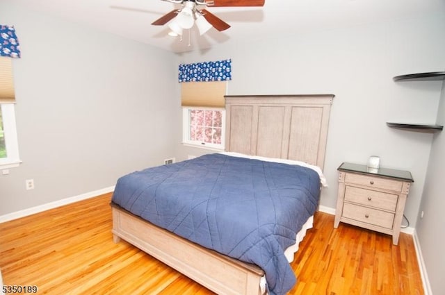 bedroom featuring baseboards, multiple windows, and wood finished floors