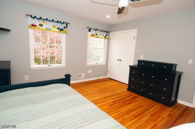 bedroom with visible vents, baseboards, wood finished floors, and a closet