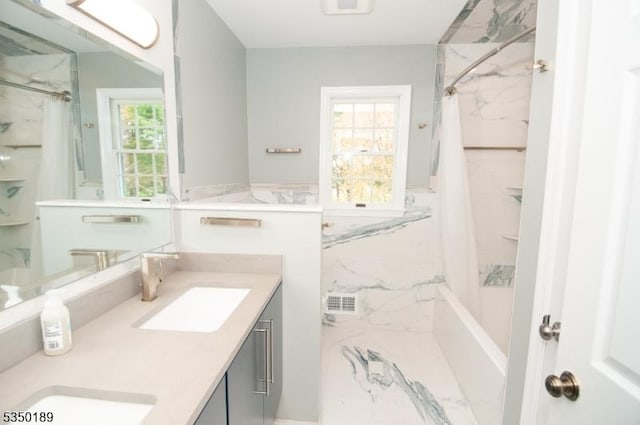 bathroom with a sink, a marble finish shower, and a healthy amount of sunlight