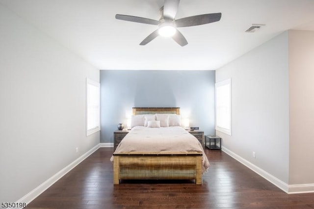 bedroom with dark wood-style flooring, visible vents, baseboards, and multiple windows