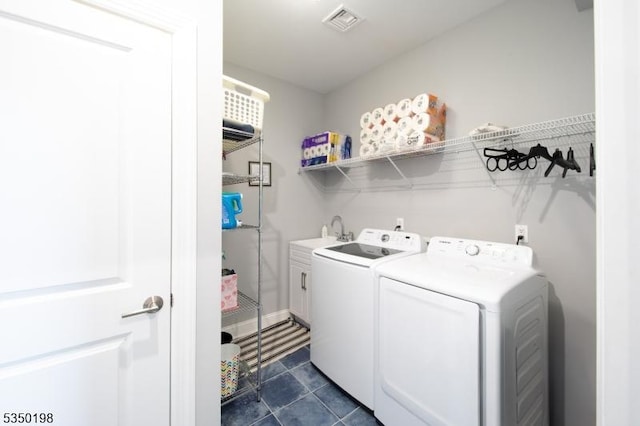 laundry area featuring visible vents, washer and dryer, a sink, cabinet space, and dark tile patterned flooring