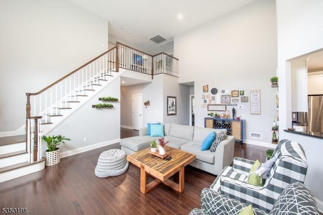 living area with stairway, a high ceiling, baseboards, and wood finished floors
