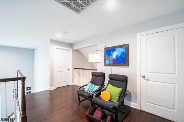 sitting room featuring an upstairs landing, visible vents, baseboards, and wood finished floors