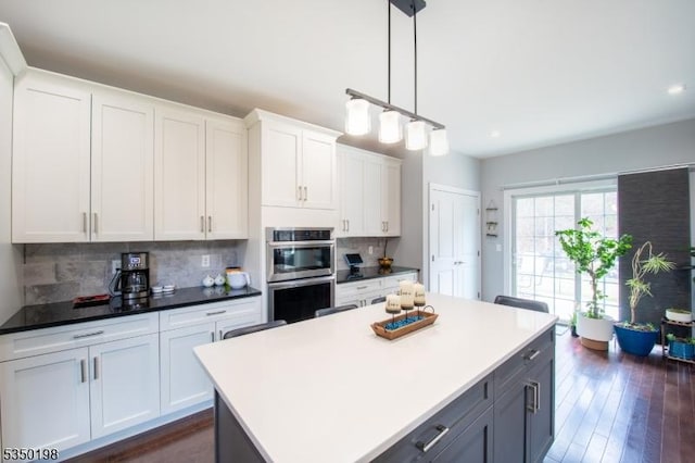 kitchen with white cabinets, decorative backsplash, double oven, and a kitchen island