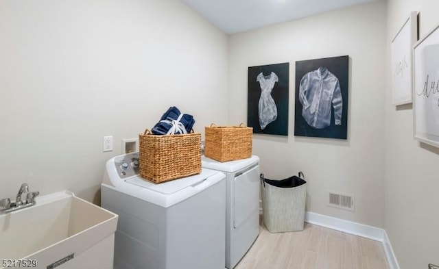 laundry room with visible vents, baseboards, a sink, laundry area, and washing machine and clothes dryer