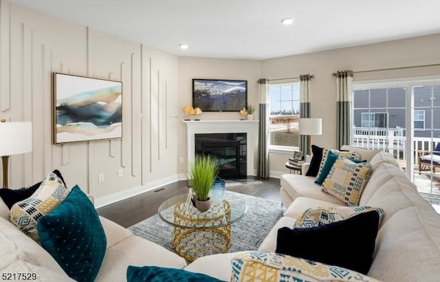 living room featuring baseboards, recessed lighting, a glass covered fireplace, and wood finished floors