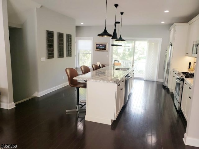 kitchen with a breakfast bar area, a wealth of natural light, a sink, stainless steel appliances, and a kitchen island with sink