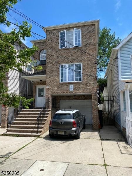 425 Fulton St, Elizabeth City, NJ 07206 - view of front of property featuring brick siding, driveway, and a garage