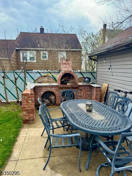 view of patio featuring a brick fireplace and fence