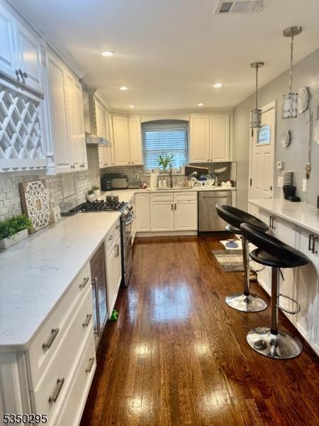 kitchen featuring dishwasher, dark wood-style flooring, white cabinetry, tasteful backsplash, and wall chimney exhaust hood