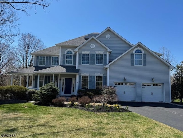 view of front facade with a front yard, an attached garage, and aphalt driveway