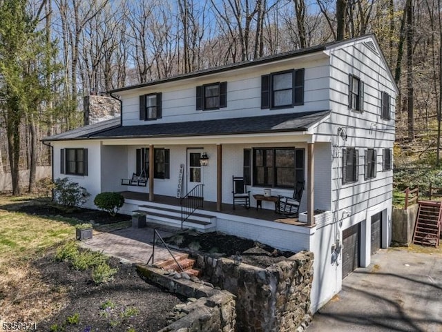 view of front of house featuring driveway, a porch, a shingled roof, and a garage