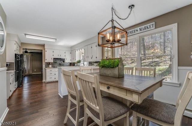 dining area with ceiling fan with notable chandelier and dark wood-style flooring