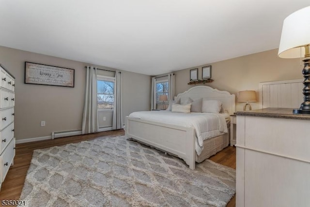 bedroom with a baseboard heating unit, baseboards, and wood finished floors
