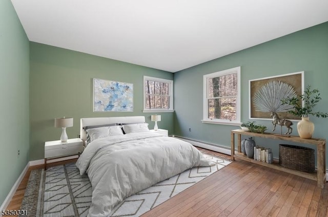 bedroom with hardwood / wood-style floors, baseboard heating, and baseboards