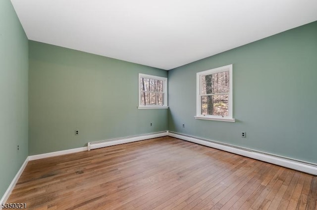 empty room with a baseboard radiator, wood finished floors, and baseboards
