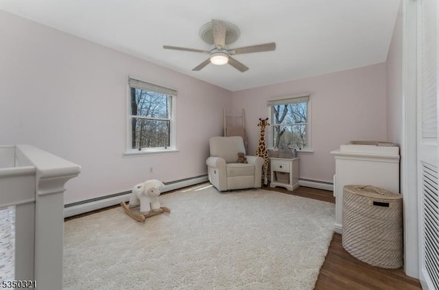 living area featuring baseboard heating, wood finished floors, and ceiling fan