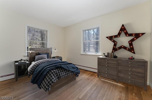 bedroom featuring a baseboard radiator, wood-type flooring, and baseboards