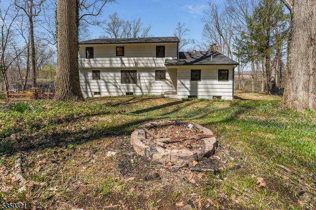 rear view of property with a chimney, crawl space, and a lawn