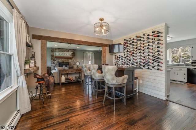 interior space featuring dark wood-type flooring, a fireplace, baseboard heating, and a notable chandelier