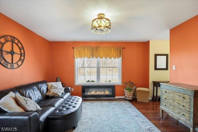 living area featuring wood finished floors, baseboards, and a glass covered fireplace