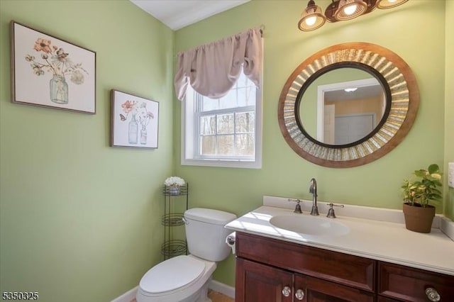 bathroom featuring toilet, vanity, and baseboards