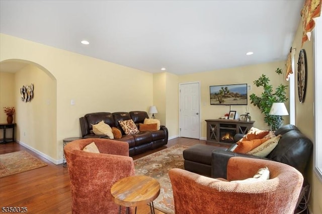 living area featuring arched walkways, wood finished floors, baseboards, and recessed lighting