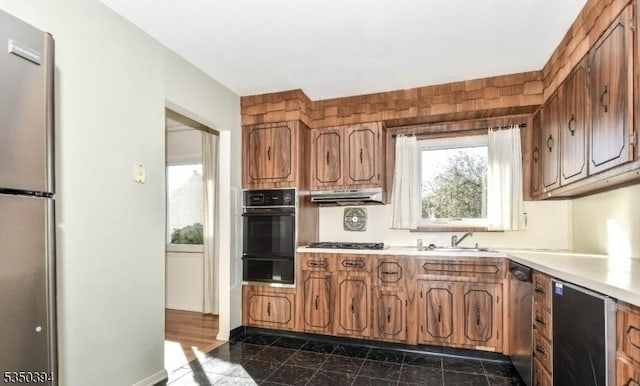 2462 Woodside Rd, Union Twp, NJ 07083 - kitchen with black oven, under cabinet range hood, a sink, and brown cabinetry