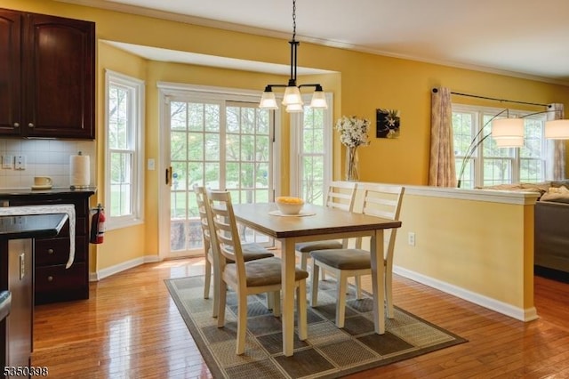 dining room with light wood-type flooring, baseboards, and crown molding