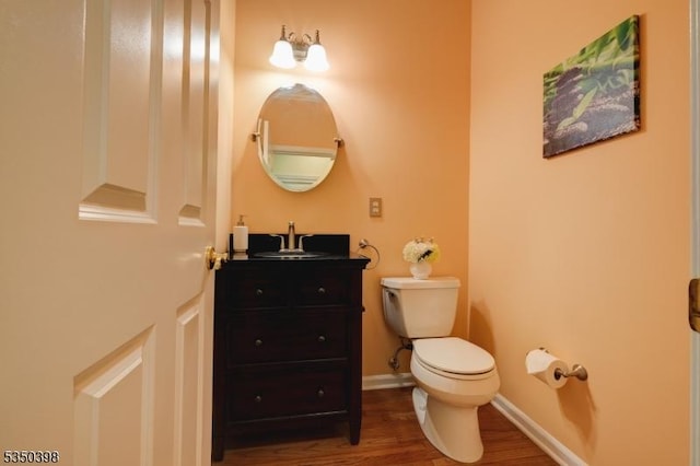 bathroom with toilet, wood finished floors, and vanity
