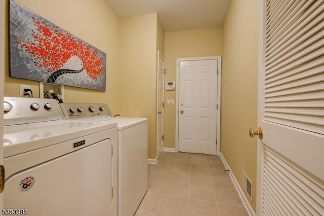 washroom featuring independent washer and dryer, light tile patterned floors, and baseboards