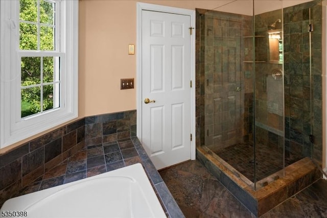 full bathroom with a stall shower, plenty of natural light, a bath, and stone finish flooring