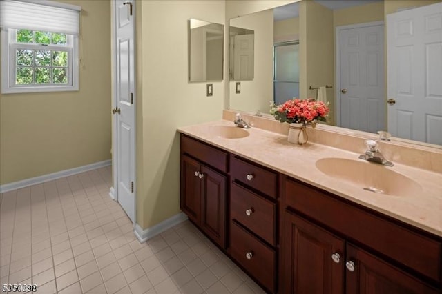 full bath featuring tile patterned floors, baseboards, double vanity, and a shower with shower door