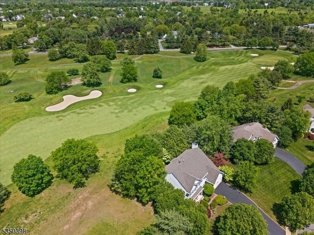 aerial view of property's location featuring a golf club and a tree filled landscape