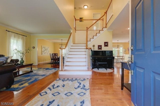 entryway featuring light wood-type flooring, stairway, crown molding, and baseboards